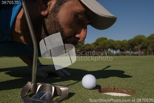 Image of golf player blowing ball in hole