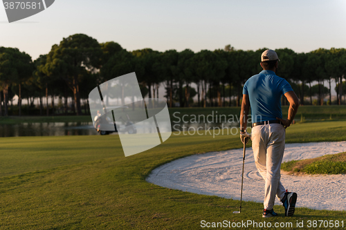 Image of golfer from back at course looking to hole in distance