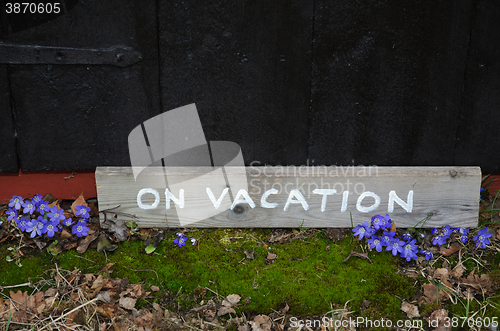 Image of On vacation sign by blue flowers