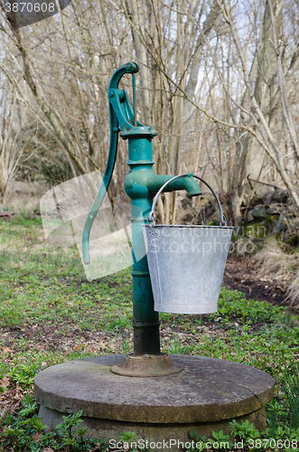 Image of Old hand water pump with a bucket