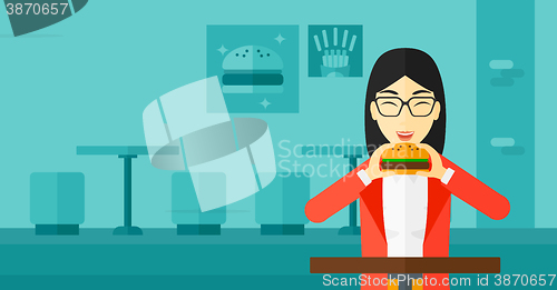 Image of Woman eating hamburger. 