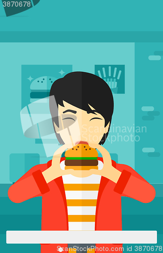 Image of Man eating hamburger. 