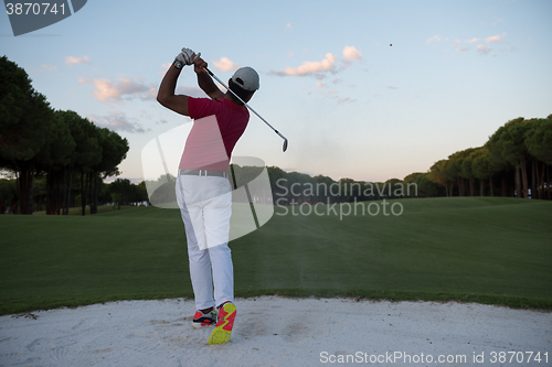 Image of golfer hitting a sand bunker shot on sunset