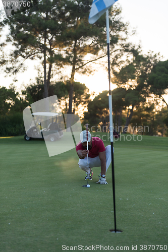 Image of golf player aiming perfect  shot on beautiful sunset