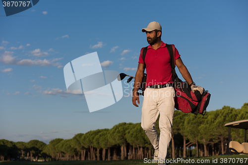 Image of golfer  walking and carrying golf  bag