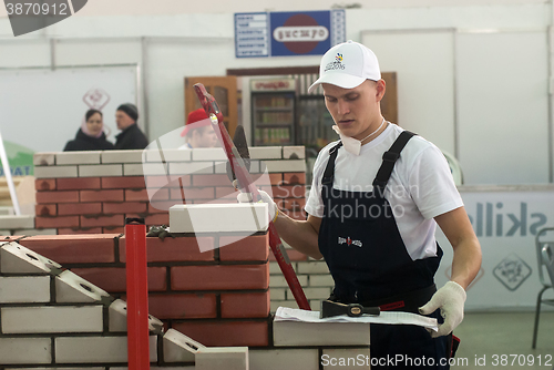 Image of Young bricklayer performs a task of competition