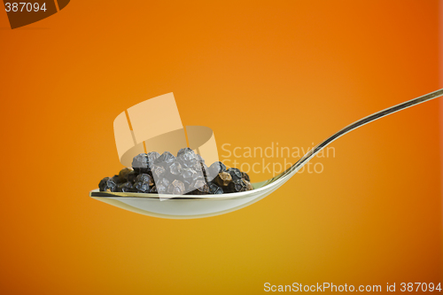 Image of spoon filled with black peppers