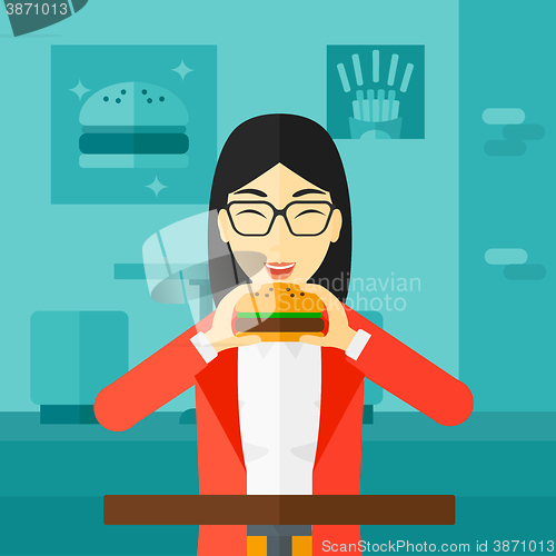 Image of Woman eating hamburger. 