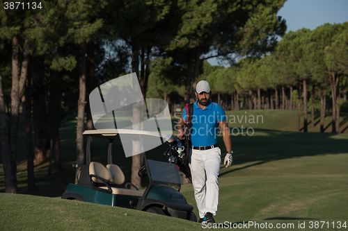 Image of golfer  walking and carrying golf  bag