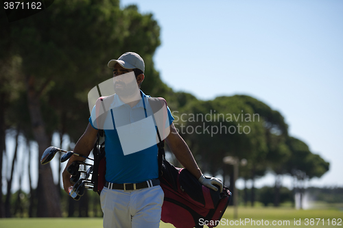 Image of golf player walking and carrying bag
