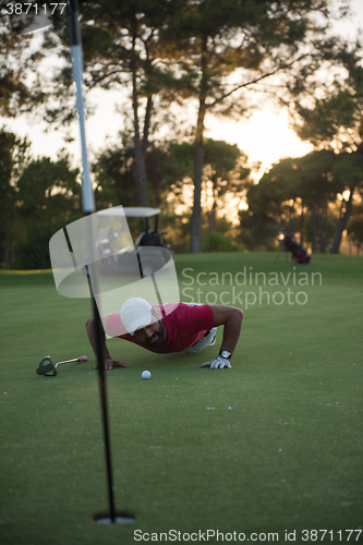 Image of golf player blowing ball in hole with sunset in background