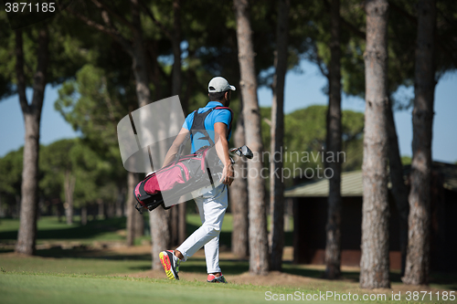 Image of golf player walking and carrying bag