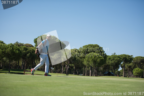 Image of golf player walking and carrying bag