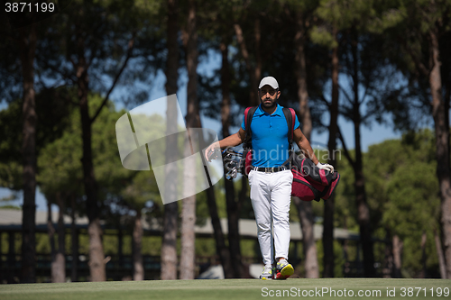 Image of golf player walking and carrying bag