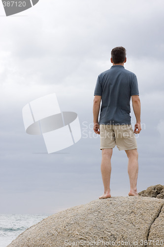 Image of Man standing on a rock at the sea