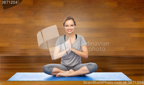 Image of woman making yoga meditation in lotus pose on mat