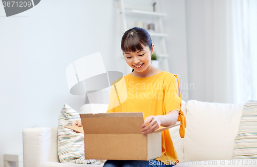 Image of happy asian young woman with parcel box at home