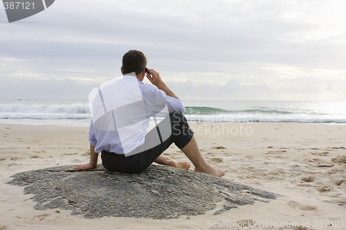 Image of Businessman with cell phone on beach