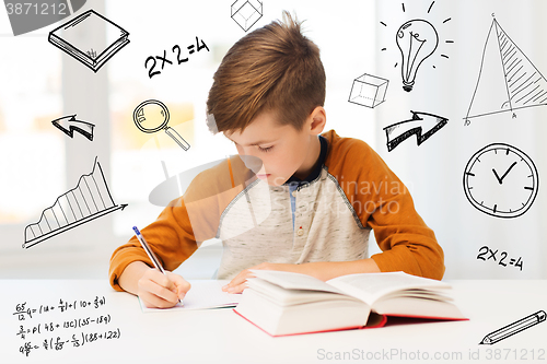 Image of student boy with book writing to notebook at home