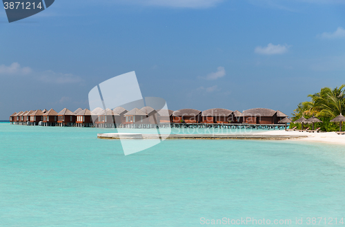 Image of bungalow huts in sea water on exotic resort beach