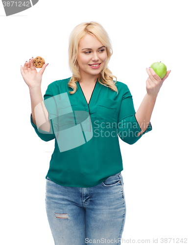 Image of smiling woman choosing between apple and cookie