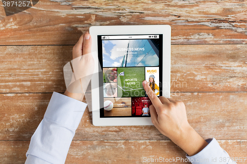 Image of close up of hands with news app on tablet pc