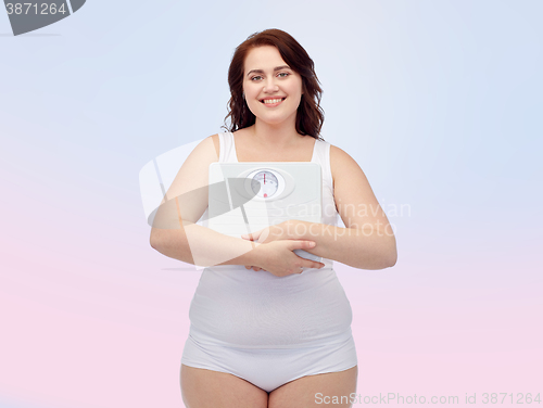 Image of happy young plus size woman holding scales