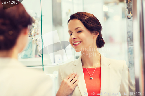 Image of happy woman choosing pendant at jewelry store