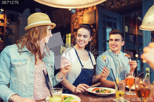 Image of happy friends eating and drinking at bar or pub