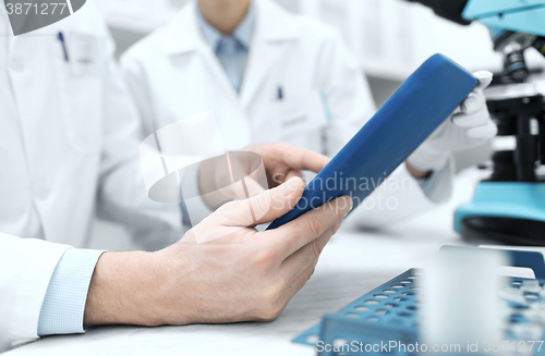 Image of close up of scientists hands with tablet pc in lab