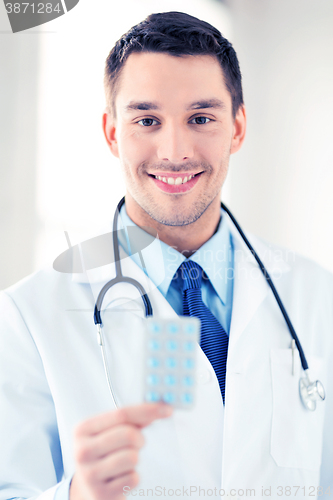 Image of young male doctor with pack of pills