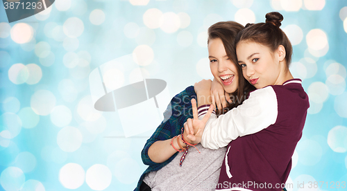 Image of happy teenage girls hugging and showing peace sign