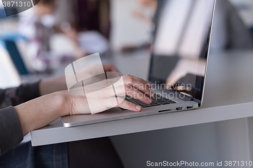 Image of close up of business womans hand typing on laptop with team on m