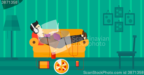 Image of Man lying on sofa with many gadgets.