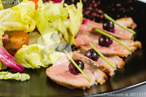 Image of grilled meat with lettuce. on black plate