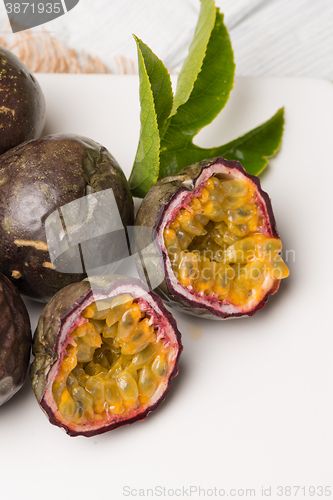 Image of Passion fruits on white ceramic tray on wooden table background.