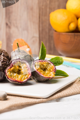 Image of Passion fruits on white ceramic tray on wooden table background.