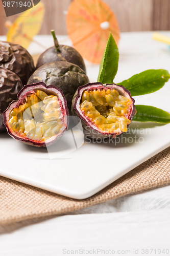 Image of Passion fruits on white ceramic tray on wooden table background.