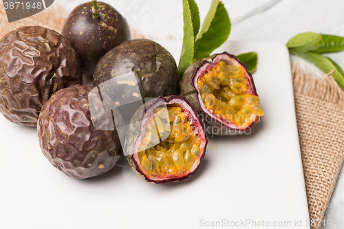 Image of Passion fruits on white ceramic tray on wooden table background.