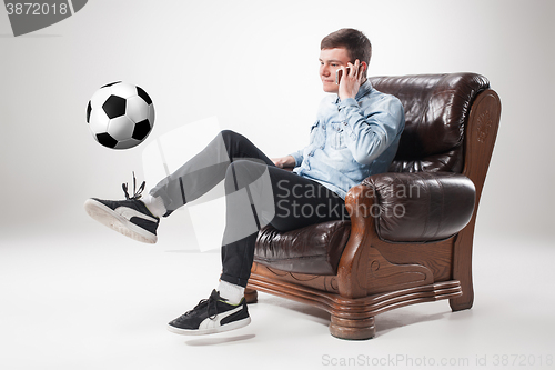 Image of The portrait of fan with ball, holding  tv remote on white background