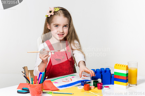 Image of Cute little girl drawing with paint and paintbrush at home