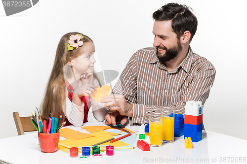 Image of The daughter and father carving out paper applications 