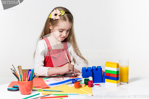 Image of Cute little girl drawing with paint and paintbrush at home