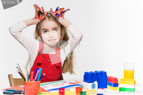 Image of The beautiful little girl with hands in the paint