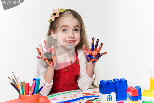 Image of The beautiful little girl with hands in the paint