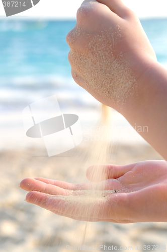 Image of Hands pouring sand on a beach