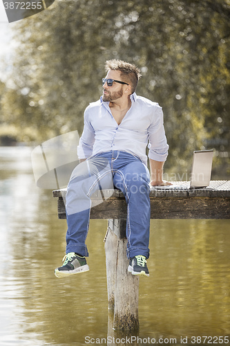 Image of man at the lake with notebook