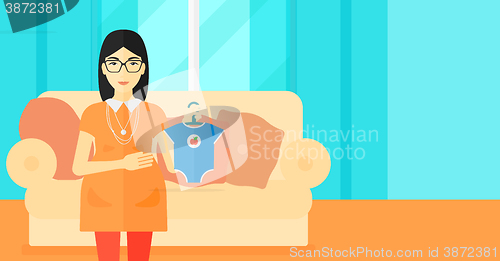 Image of Pregnant woman with clothes for baby.