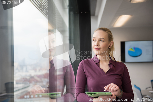 Image of blonde businesswoman working on tablet at office