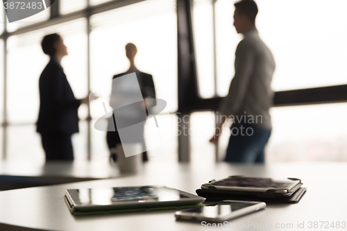 Image of close up of tablet, business people on meeting in background